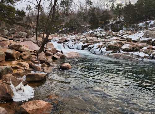 A serene river scene with icy rocks and a gentle waterfall, surrounded by trees and winter scenery.