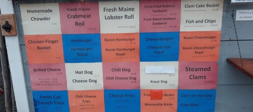 Menu board featuring seafood and comfort food items with prices, including chowder, crab rolls, and burgers.