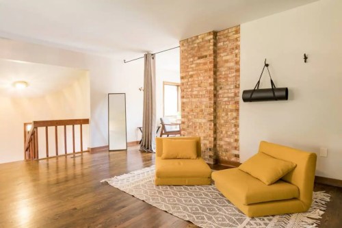 Cozy living space featuring yellow seating, a brick wall, and natural light from a nearby window.