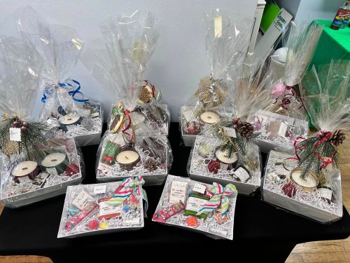 A display of gift baskets wrapped in cellophane, filled with candles and decorative items, arranged on a table.