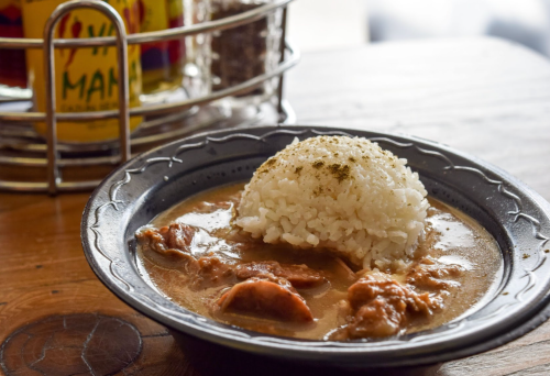 A plate of rice topped with a savory meat stew, served on a rustic wooden table.