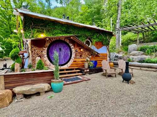 A whimsical, nature-inspired tiny house with a round purple door, surrounded by greenery and outdoor seating.