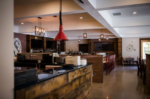 A modern restaurant interior featuring a bar, wooden accents, and stylish lighting.