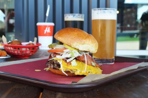 A juicy cheeseburger with toppings, served on a tray alongside drinks and a basket of appetizers.