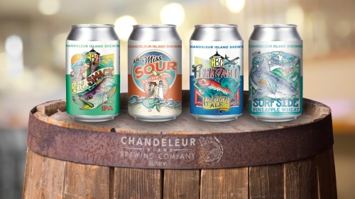 Four colorful beer cans from Chandeleur Island Brewing Company displayed on a wooden barrel.