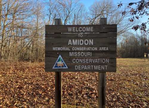 Wooden sign welcoming visitors to Amidon Memorial Conservation Area in Missouri, surrounded by trees and fallen leaves.