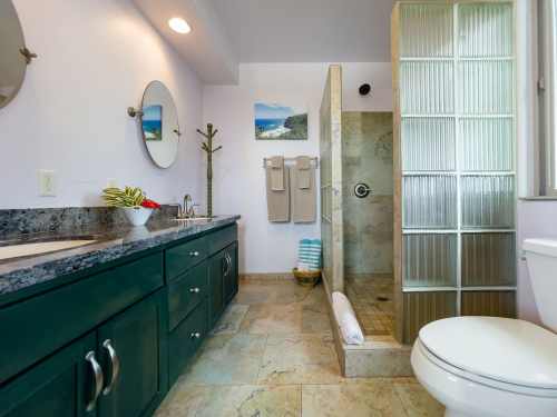 Modern bathroom featuring a glass shower, dark cabinetry, and natural light from a window.