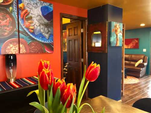 Brightly colored interior featuring red tulips, vibrant wall art, and a cozy seating area in the background.