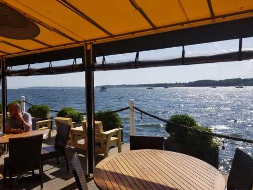 A sunny waterfront view from a restaurant, featuring boats on the water and a bright yellow awning overhead.