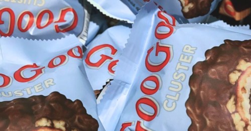A close-up of several packages of GooGoo Clusters, featuring a chocolate-covered treat with a logo on the wrappers.