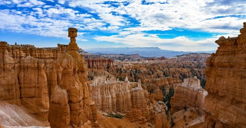 A stunning view of Bryce Canyon, featuring unique rock formations under a blue sky with scattered clouds.