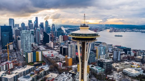 Aerial view of Seattle featuring the Space Needle, city skyline, and waterfront under a cloudy sky.