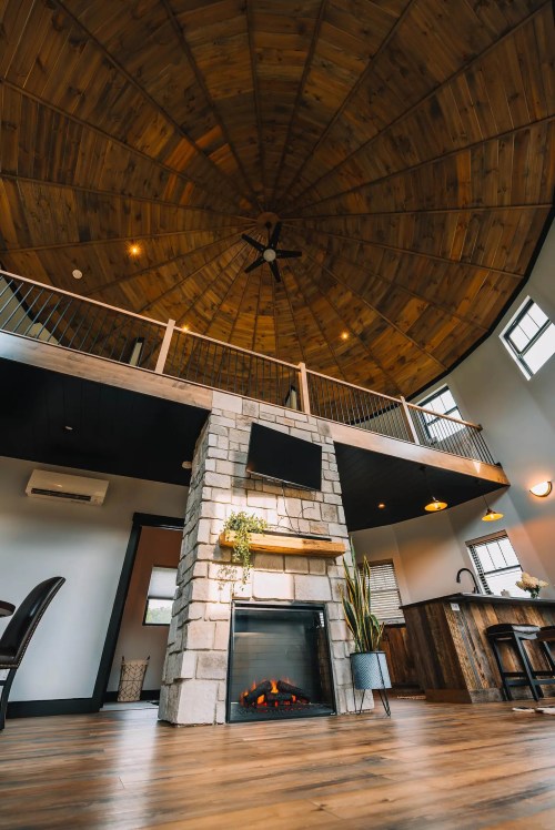 A cozy interior with a circular wooden ceiling, stone fireplace, and modern decor, featuring a warm and inviting atmosphere.