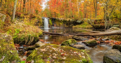 A small waterfall tumbles into a wide and slow river at Banning State Park in Minnesota.