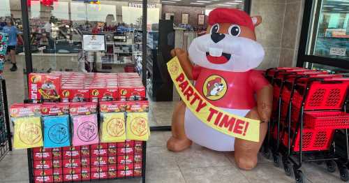 A large inflatable beaver mascot stands next to colorful party supplies and snacks in a store entrance.