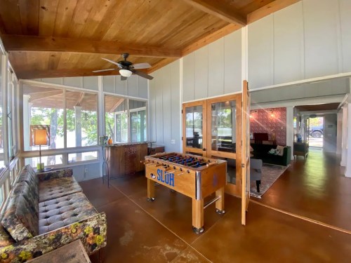 Bright, open room with a foosball table, wooden ceiling, and large windows overlooking a scenic view.