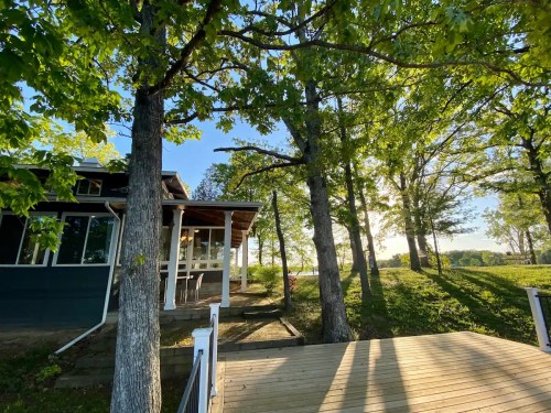 A serene outdoor view of a house surrounded by trees, with sunlight filtering through the leaves.