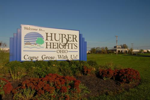 Welcome sign for Huber Heights, Ohio, with colorful flowers and a clear blue sky in the background.