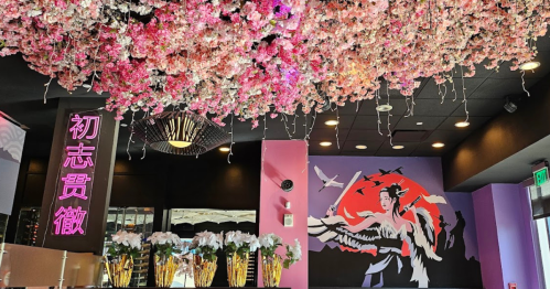 A vibrant interior with a floral ceiling, pink walls, and a mural of a woman against a red backdrop.