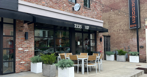 Exterior of a brick restaurant with outdoor seating and planters, featuring a sign that reads "Bourbon's Bistro."