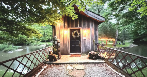 A cozy wooden cabin by a serene river, surrounded by lush greenery and soft evening lights.