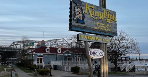 Sign for KingFish restaurant with a riverside view, featuring a bar and nearby bridge in the background.