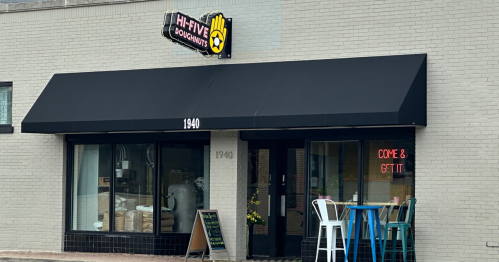 Exterior of Hi-Five Doughnuts shop with a black awning, bright sign, and a "Come & Get It" neon display.