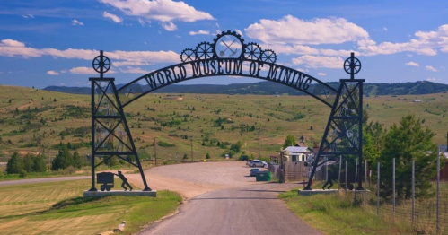 Archway sign for the World Museum of Mining, set against a scenic landscape with rolling hills and blue skies.