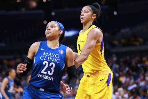 Two female basketball players in action during a game, one in a blue jersey and the other in a yellow jersey.