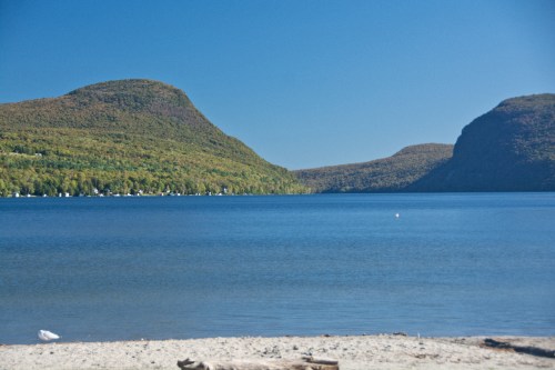 A serene lake surrounded by lush green mountains under a clear blue sky.