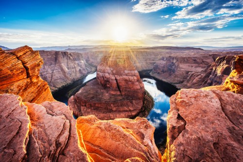 A stunning sunset over Horseshoe Bend, showcasing dramatic rock formations and a winding river below.