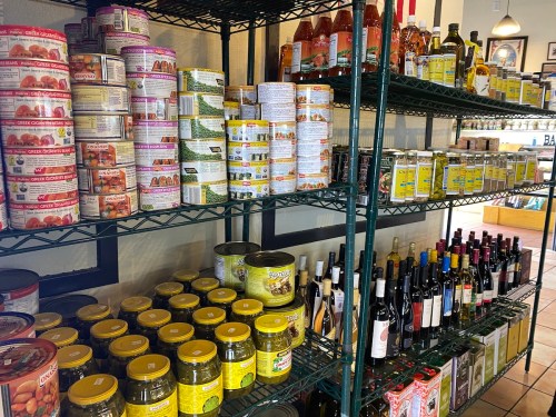 Shelves filled with various canned goods, sauces, and bottles of wine in a grocery store.