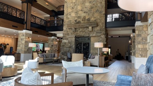 A spacious hotel lobby featuring stone walls, modern furniture, and large windows, creating a welcoming atmosphere.