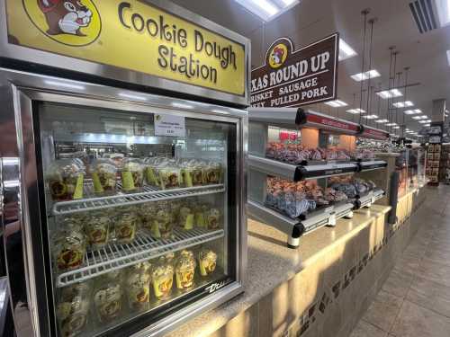 A display of cookie dough jars at a station, with a sign for brisket, sausage, and pulled pork nearby.