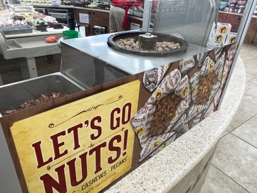 A display of nuts with a sign that says "Let's Go Nuts!" featuring almonds, cashews, and pecans.