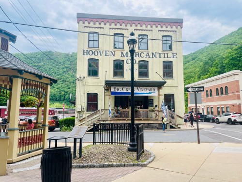 Historic Hooven Mercantile building with a vineyard sign, surrounded by green mountains and a bustling street scene.