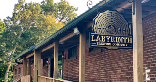 Sign for Labyrinth Brewing Company on a brick building with trees in the background.