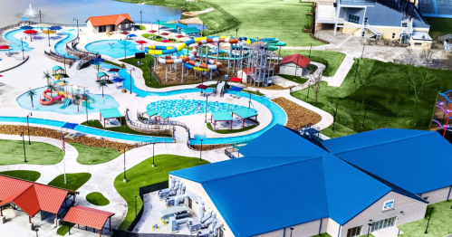Aerial view of a vibrant water park featuring slides, pools, and colorful attractions surrounded by green lawns.