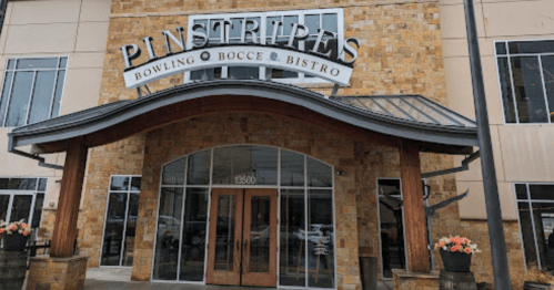 Exterior view of Pinstripes, a bowling and bistro venue, featuring a stone facade and large entrance.