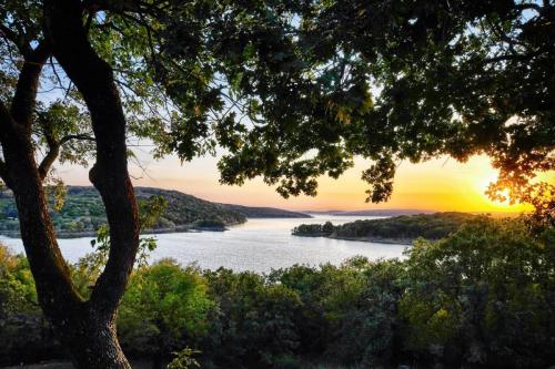 A serene lake view at sunset, framed by trees, with vibrant colors reflecting on the water.