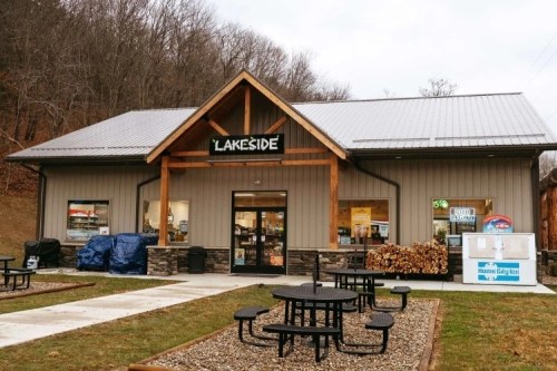 A cozy building with a sign reading "Lakeside," featuring outdoor seating and stacked firewood.