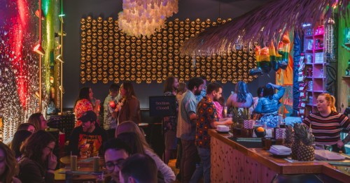 A lively crowd enjoys cocktails at the thatched bar inside Mai Tiki, a hidden speakeasy in Ferndale.