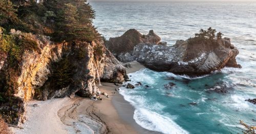 Aerial view of the thin McWay Falls pouring out into the ocean at Big Sur in Northern California