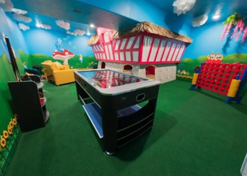 Colorful playroom with a large air hockey table, vibrant wall murals, and a cozy seating area.