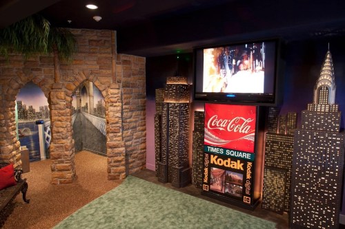 A themed room featuring a stone archway, a TV, and a display with Coca-Cola and Kodak advertisements against a cityscape backdrop.