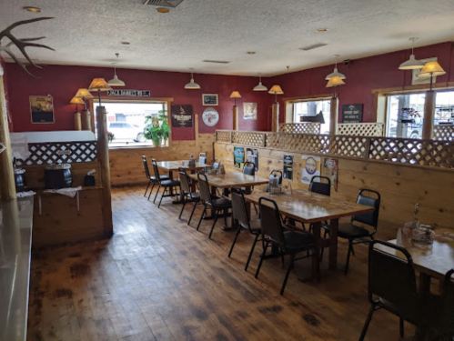 Cozy restaurant interior with wooden tables, chairs, and warm lighting, featuring a rustic decor and a welcoming atmosphere.