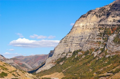 A scenic view of rugged mountains under a clear blue sky, with colorful foliage in the valley below.