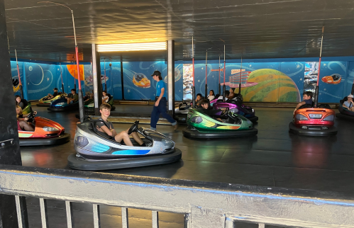 A group of people enjoying bumper cars in a colorful indoor amusement park setting.