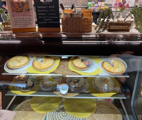 Display case with various pies, including chocolate, apple, blueberry, and lemon, on decorative plates.