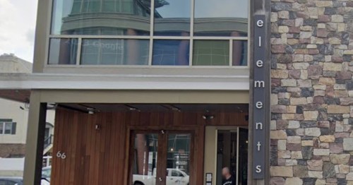 Exterior of a modern building with a stone facade and large windows, featuring the word "elements" on the side.